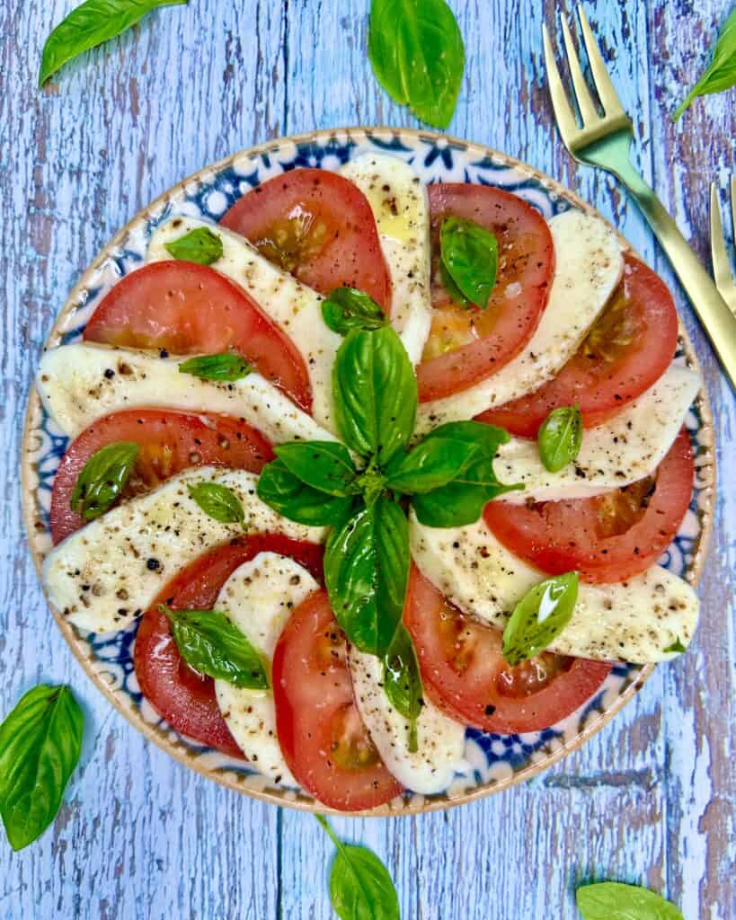 Caprese salat - tomater og mozzarella i skiver med frisk basilikum, olivenolie og friskkværnet peber.