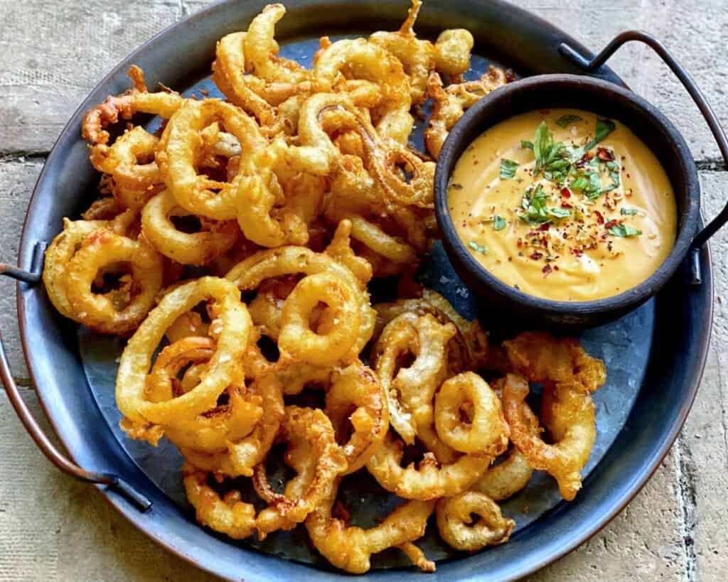 Friterede løgringe - hjemmelavede indbagte løg serveret med cheddar dip