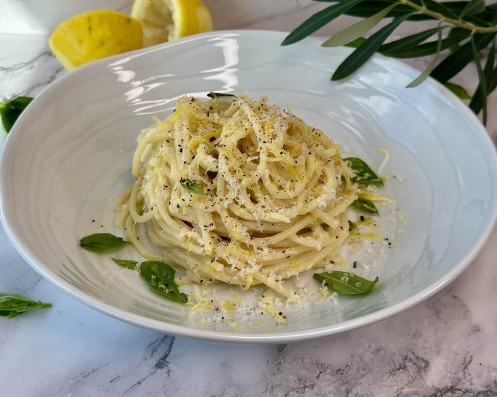 Citronpasta i tallerken med olivenolie, revet parmesan og friske basilikumsblade