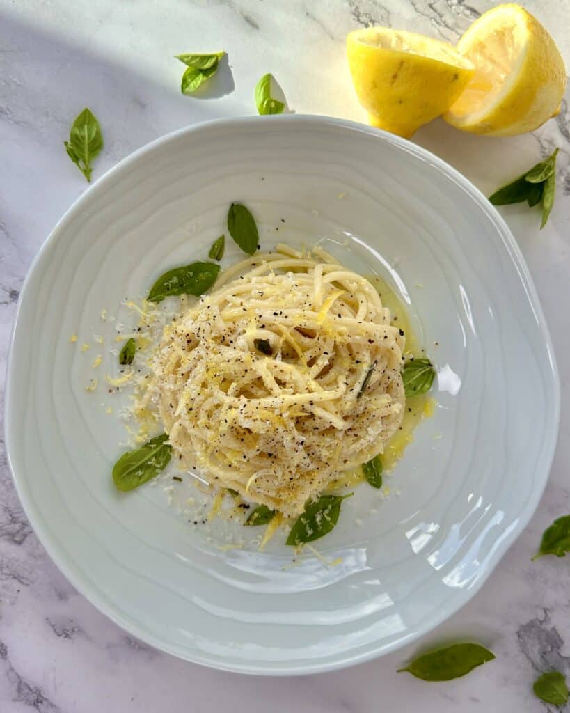 Citronpasta i tallerken med olivenolie, revet parmesan og friske basilikumsblade