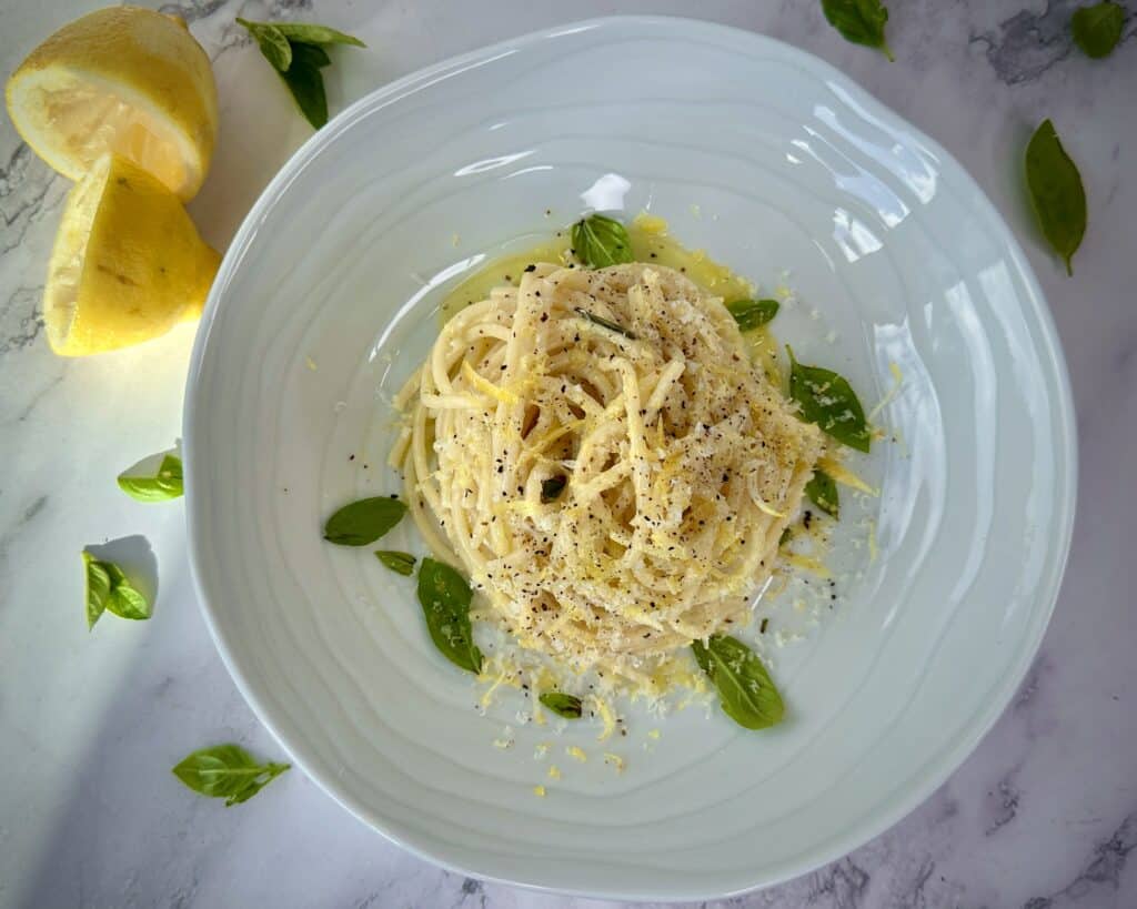 Citronpasta i tallerken med olivenolie, revet parmesan og friske basilikumsblade