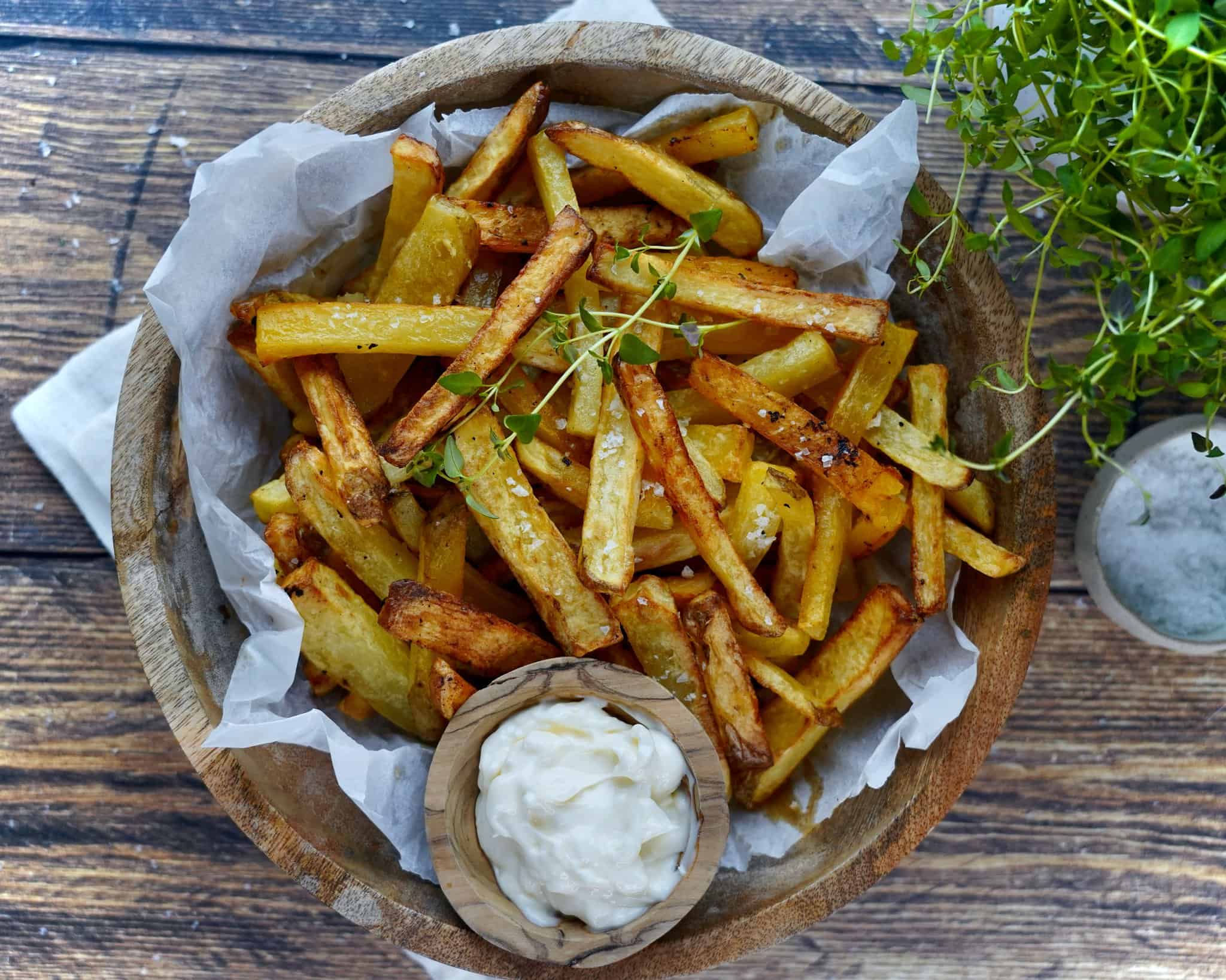 Pommes frites i airfryer serveret i træskål med salt og mayonnaise.