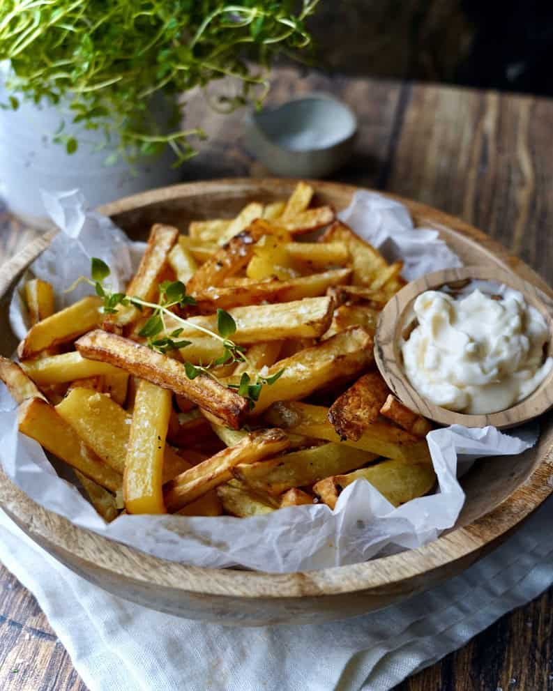 Pommes frites i airfryer serveret i træskål med salt og mayonnaise.