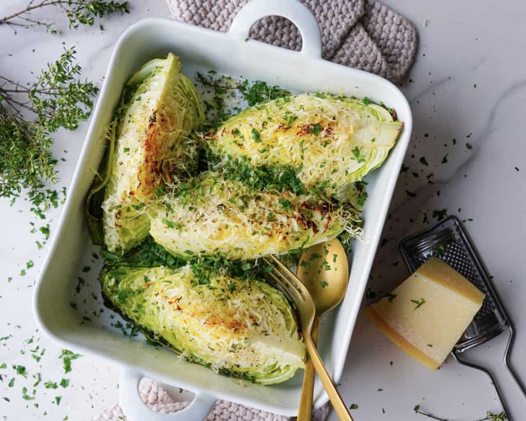 Bagt spidskål med parmesan serveret i hvidt fad med fintsnittet persille.