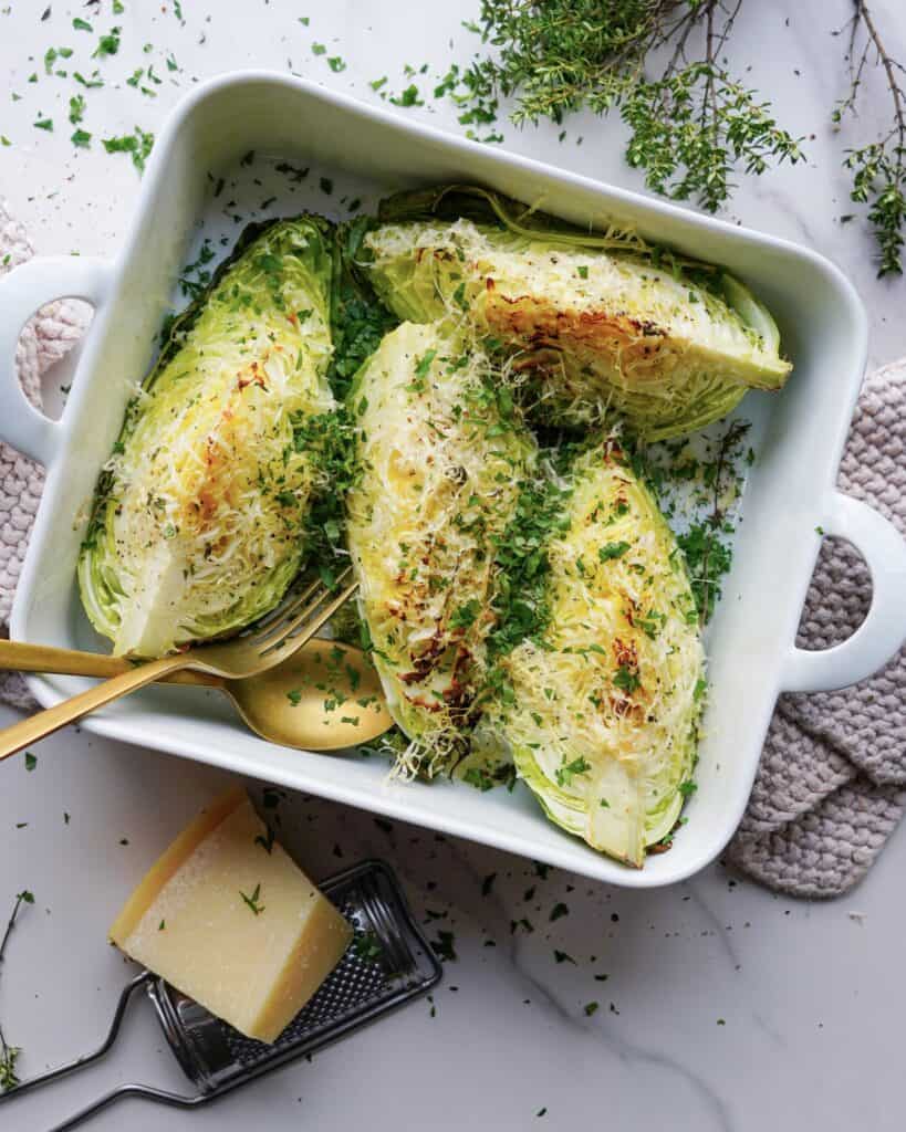 Bagt spidskål med parmesan serveret i hvidt fad med fintsnittet persille.