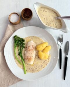 Ovndampet torsk serveret med kogte kartofler, dampet broccoli og cremet sennepssauce.