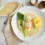 Ovndampet torsk serveret med kogte kartofler, dampet broccoli og cremet sennepssauce.