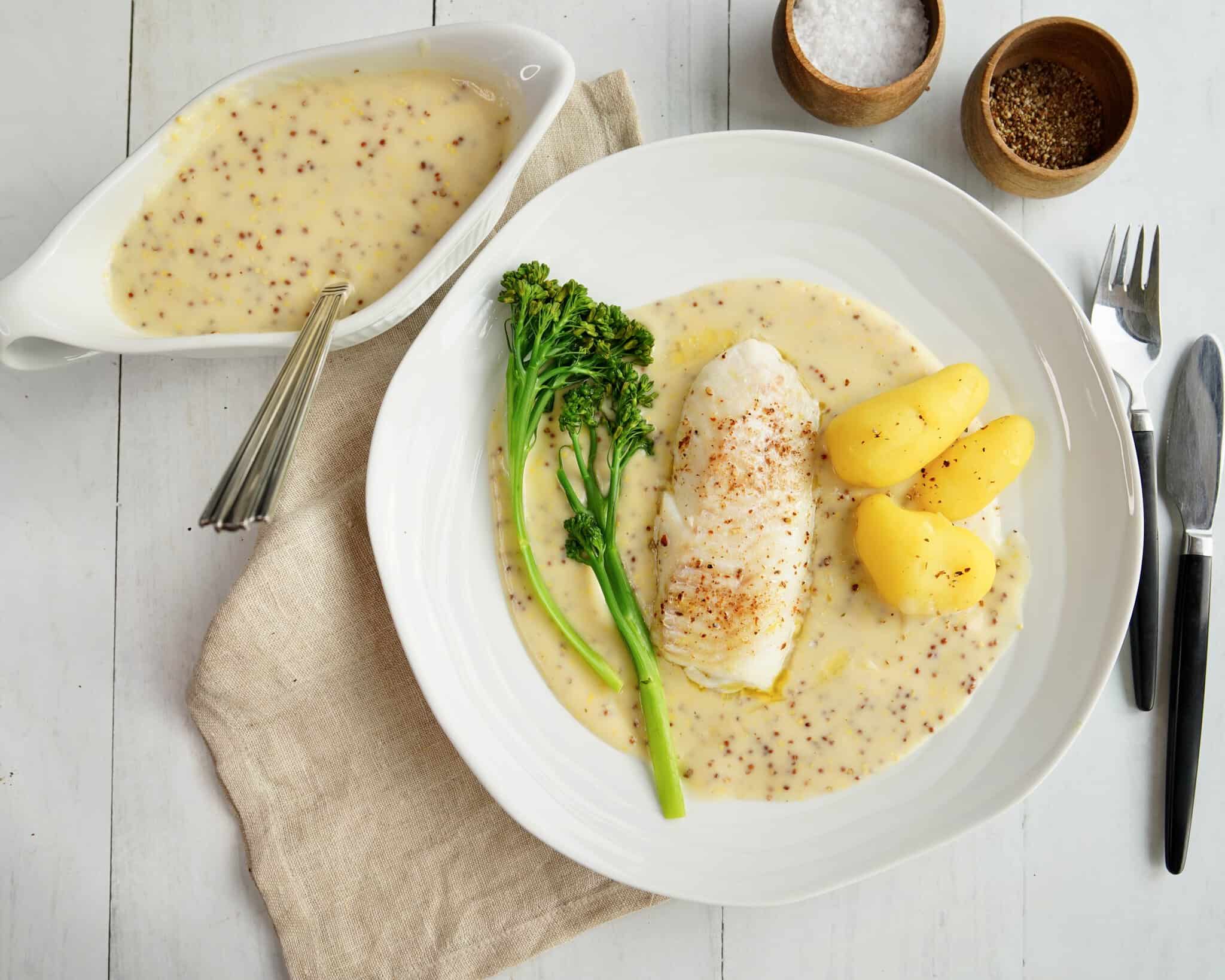 Ovndampet torsk serveret med kogte kartofler, dampet broccoli og cremet sennepssauce.