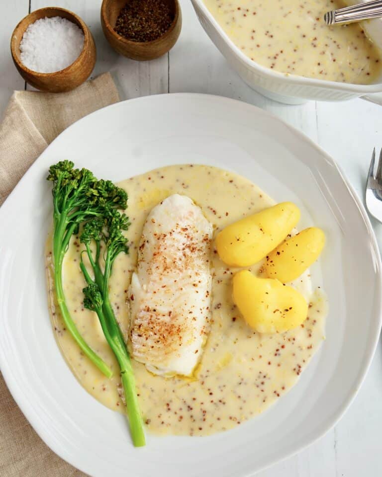 Ovndampet torsk serveret med kogte kartofler, dampet broccoli og cremet sennepssauce.
